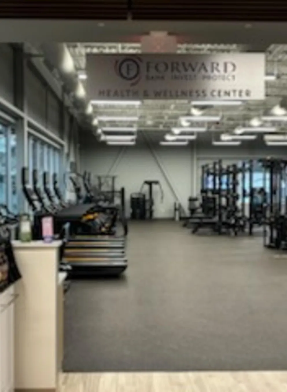 View of a "Health & Wellness Center" through doorway, showcasing cardio machines, weight training equipment, and abundant natural light.