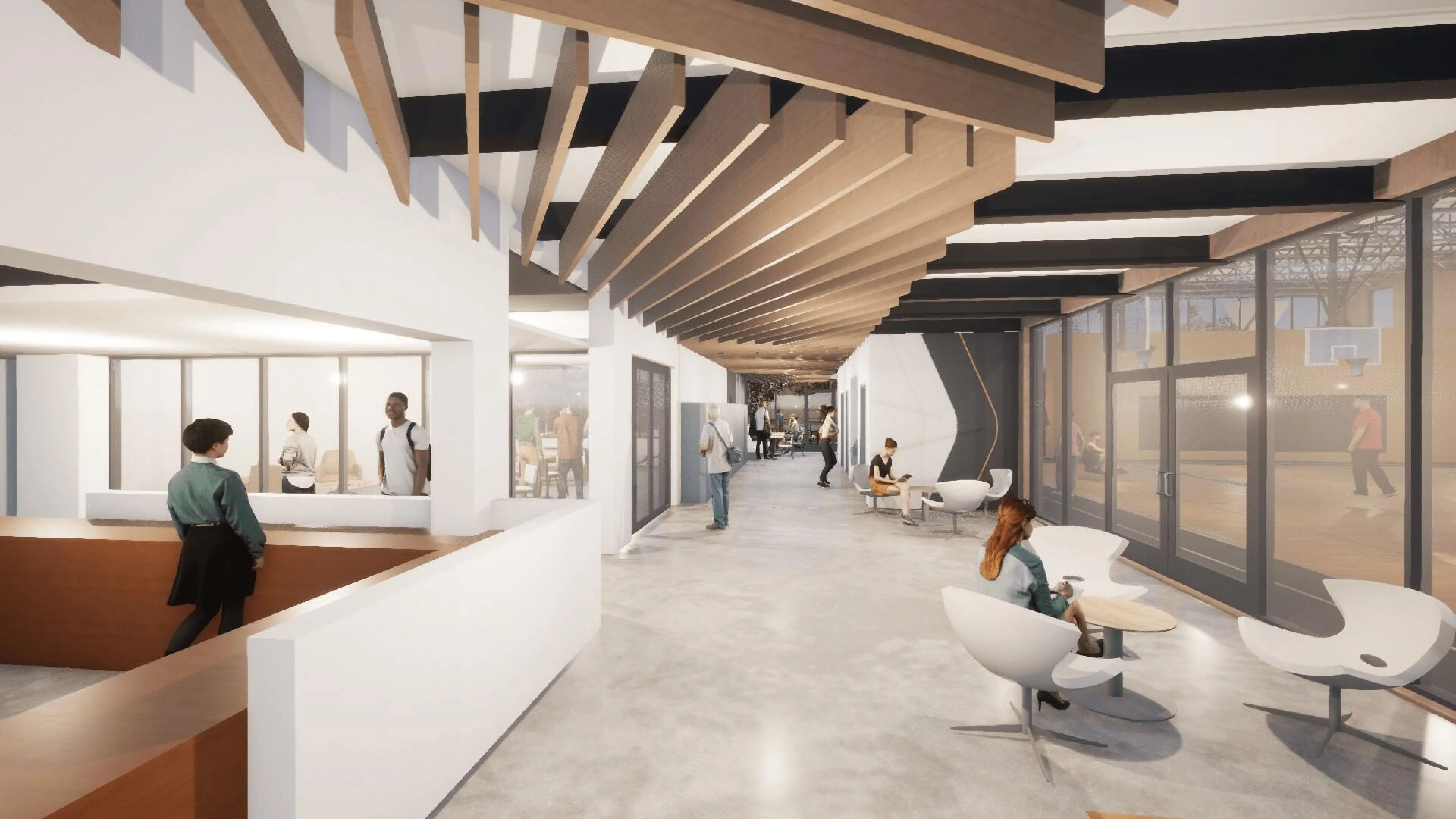 A bright, spacious hallway with wood and white accents. People are walking and sitting, some near a reception desk.  Large windows overlook a basketball court.